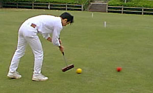 T. Nozaki plays a croquet stroke near hoop 4.