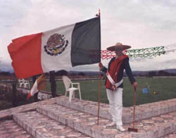 Dr. Bett Yates Adams, San Miguel resident player, USCA member-at-large, and first female publisher (retired) in the New York Times chain, hoists the flag in full regalia to dramatize the opening of Mexico's newest court.