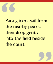 Para gliders sail from the nearby peaks, then drop gently into the field beside the court.